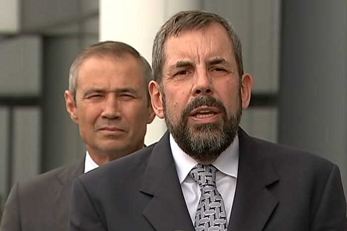 Andrew Robertson and Roger Cook at a press briefing in front of an office building.