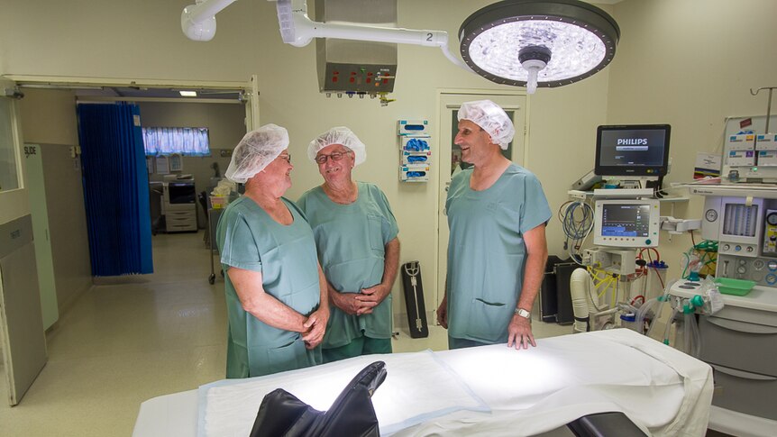 Three men in hospital gowns inside a surgery
