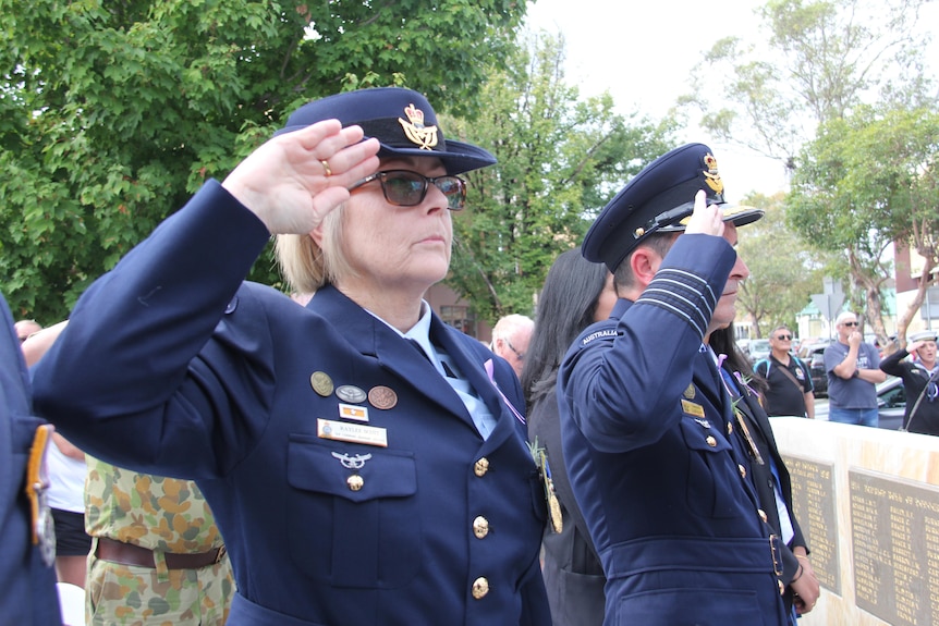 a woman in army uniform saluting at an anzac day service for women veterans
