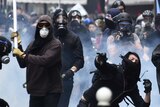 Masked protesters throw stones during a protest in Paris.