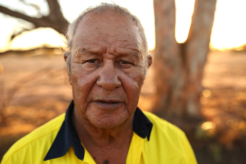 A headshot of Kevin Barron standing in the open with brown landscape in the background.