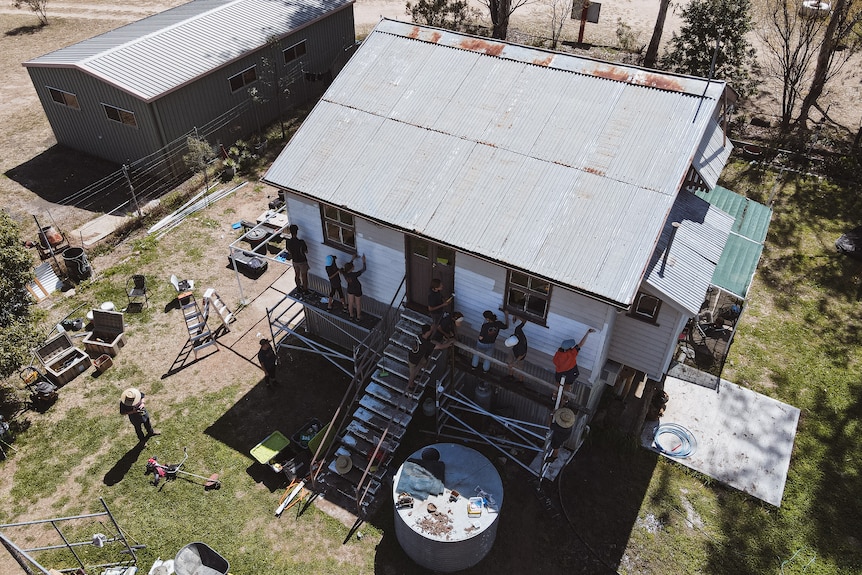 A drone shot of kids painting an old home. 