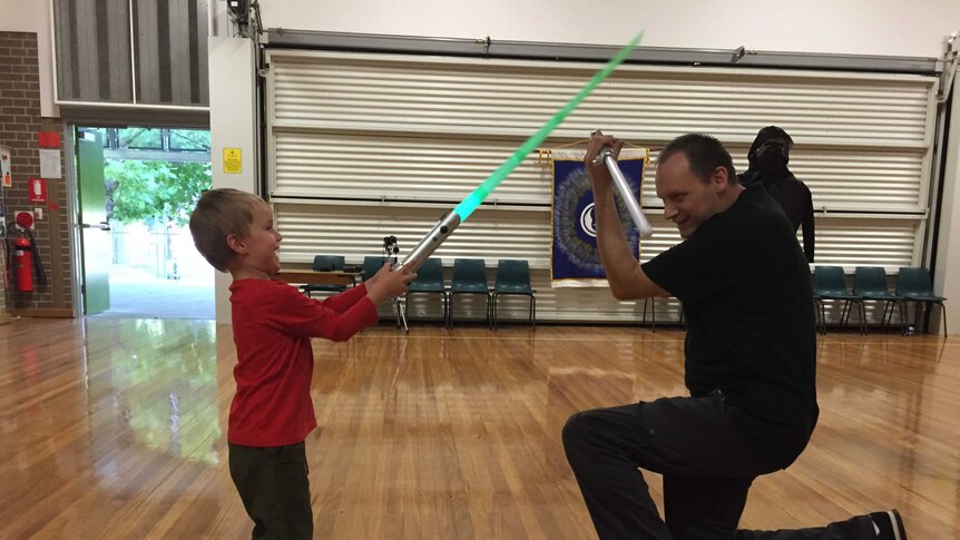 A boy and a man duelling with lightsabers