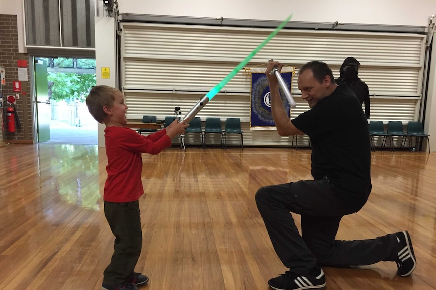 A boy and a man duelling with lightsabers