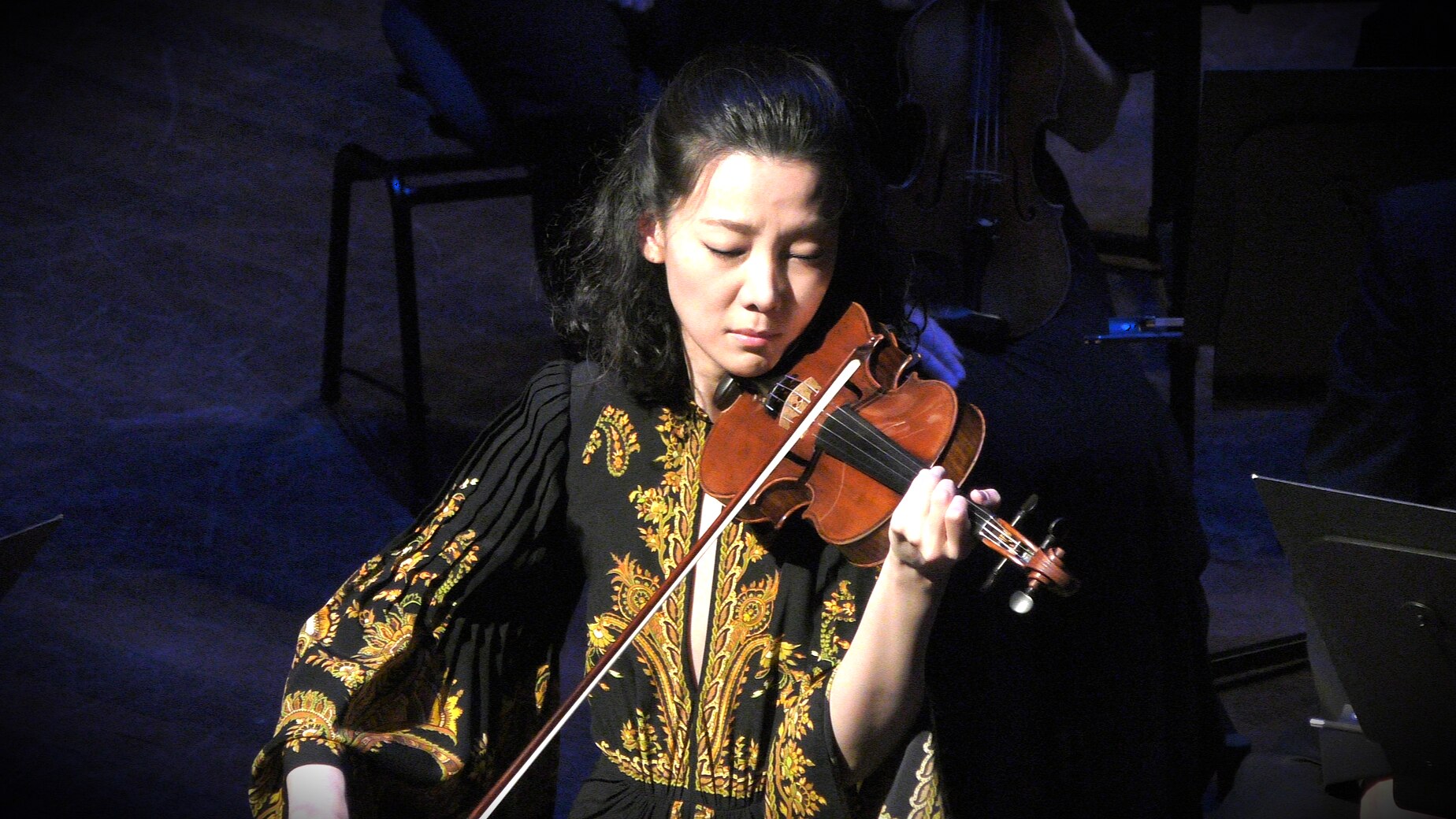 Clara-Jumi Kang playing violin in a black and gold dress