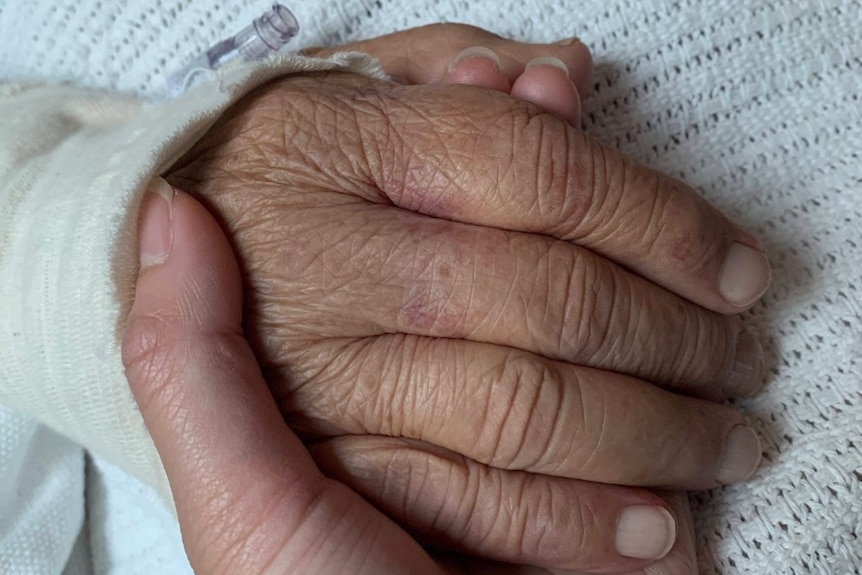 A close up of an older person's being held by another person. 