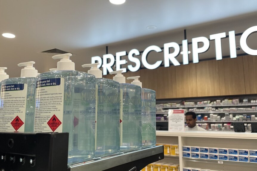 Large white lit up prescription sign with back of hand sanitiser bottles in foreground