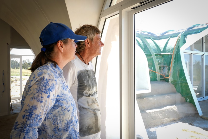 profile of couple looking out window to the unfinished exterior of their home