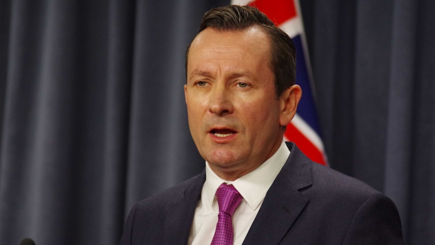 Head and shoulders shot of WA Premier Mark McGowan with a flag in the background.