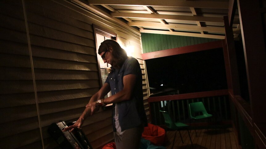 Musician stretching arm before a performance while on the verandah at night