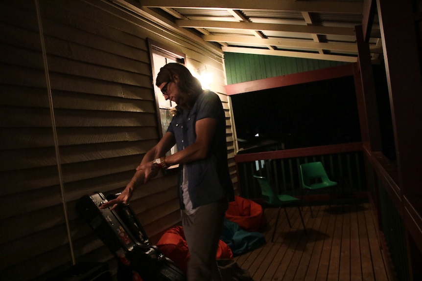 Musician stretching arm before a performance while on the verandah at night