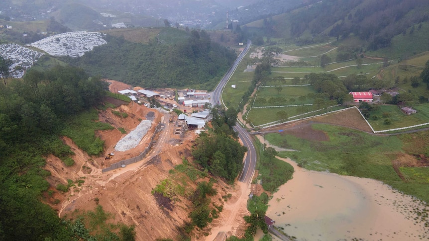 An aerial photo shows orange mud covering a road along a mountainside.