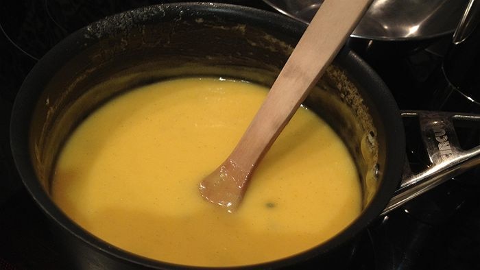 Yellow sauce simmering in a saucepan.