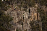 Two men abseil down a rock wall