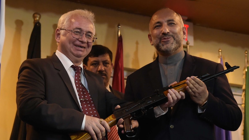 Russia hands an AK-47 to Afghan's security adviser.