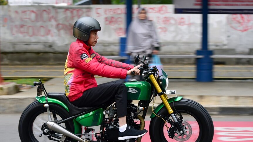 Indonesian President Joko Widodo wears a red jacket as he rides a motorbike in Bogor, Indonesia.