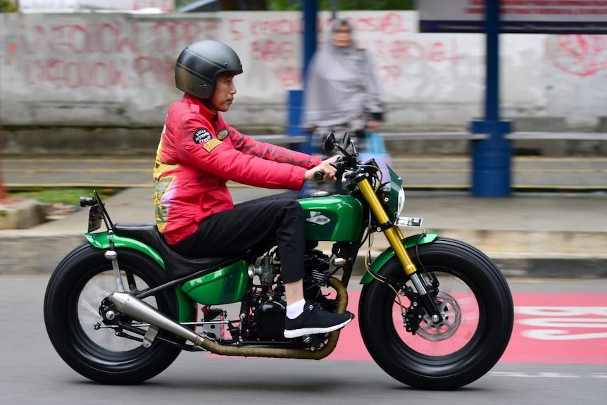 Indonesian President Joko Widodo wears a red jacket as he rides a motorbike in Bogor, Indonesia.