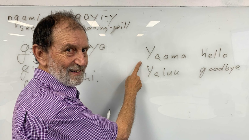 A man points to a word written on a whiteboard.