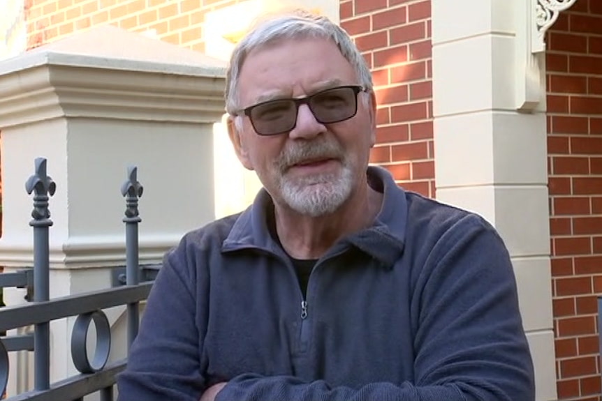 A man wearing sunglasses outside a faux heritage home