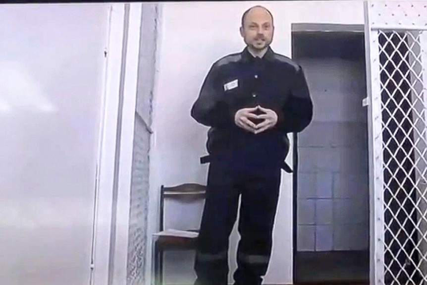 Vladimir Kara-Murza stands in front of a barred cell.
