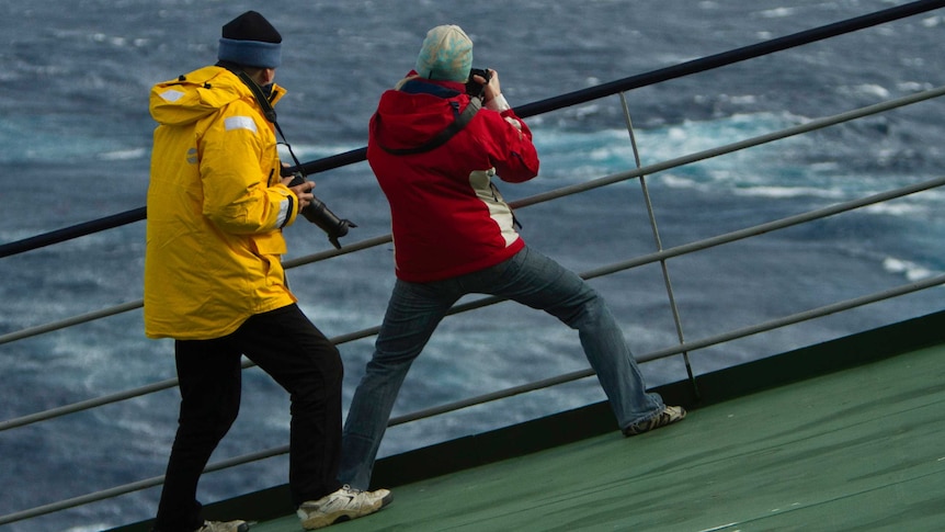 Crew members struggle to stand aboard a ship in rough weather