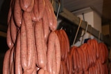 Hundreds of sausages hanging on meat hooks in a cold room.