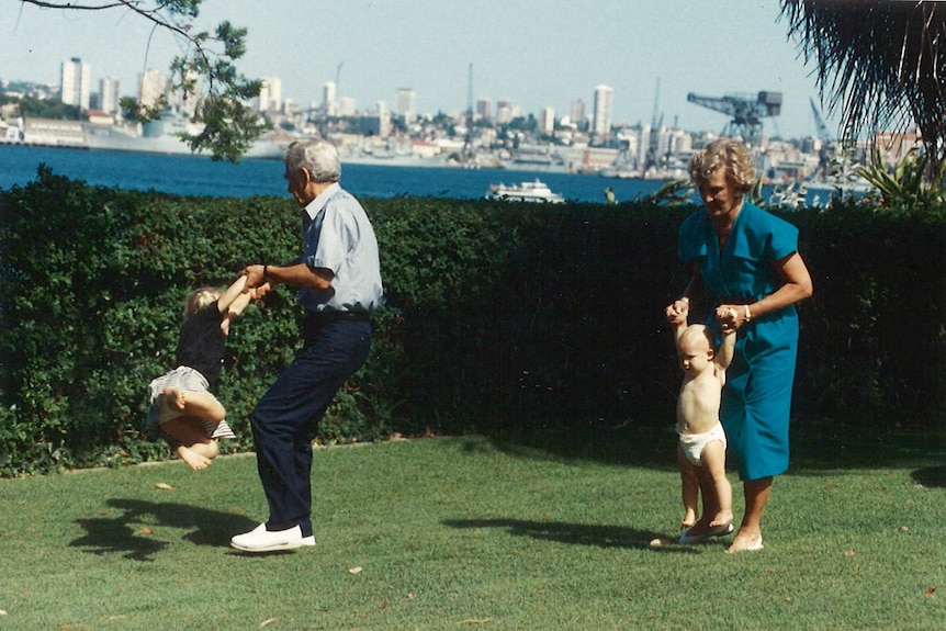 Bob and Hazel Hawke play with their grandchildren outside on grass.