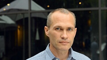 A man wearing a patterned shirt stares directly ahead.