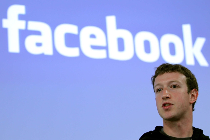 Mark Zuckerberg speaks with a Facebook logo on a screen behind him.