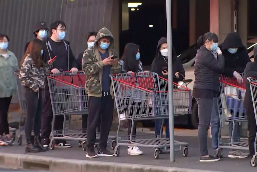 Shoppers queue the length of a shopping trolley outside Costco.