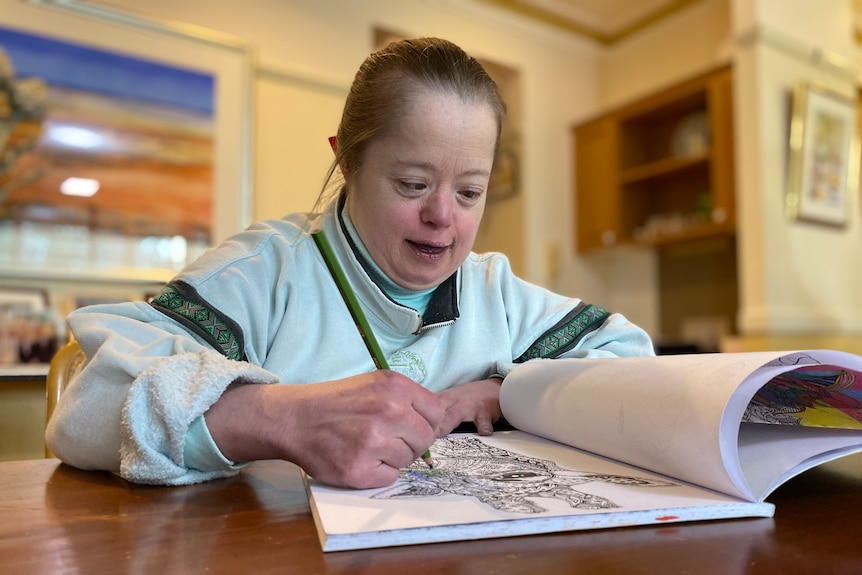 A woman colouring in at the dining table