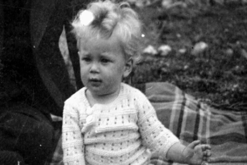 Black and white photo of Adams as a small child sitting on a picnic rug.
