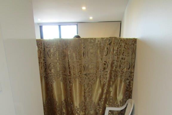 A gold curtain hides part of a room, with two white plastic chairs sitting outside.