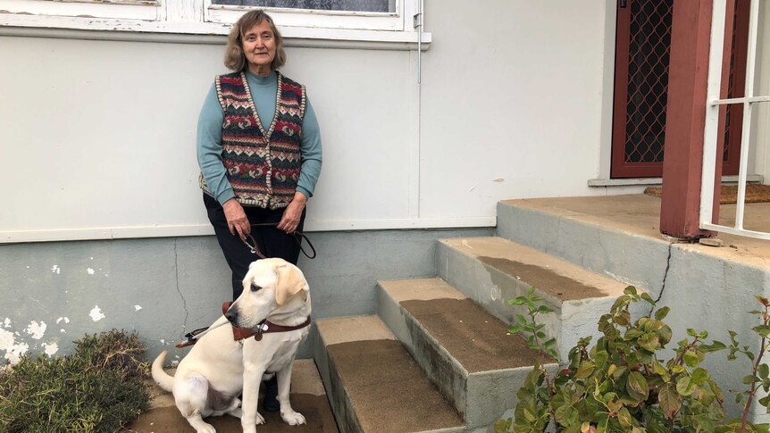 Wendy Arentz stands at the front of her home in Tumut with her guide dog.