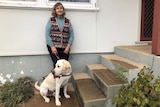 Wendy Arentz stands at the front of her home in Tumut with her guide dog.