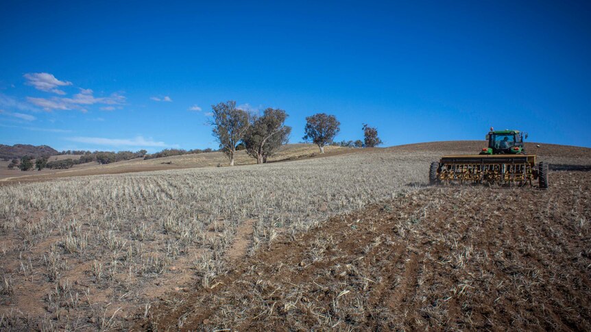 A tractor ploughing a dry paddock