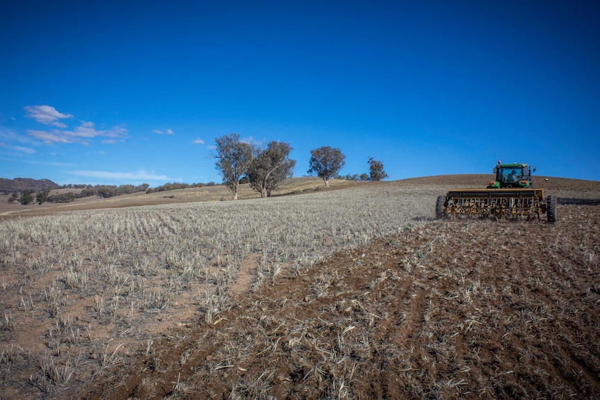 A tractor ploughing a dry paddock