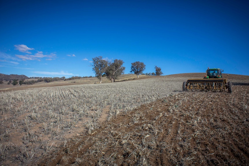 A tractor in a dry paddock planting seed