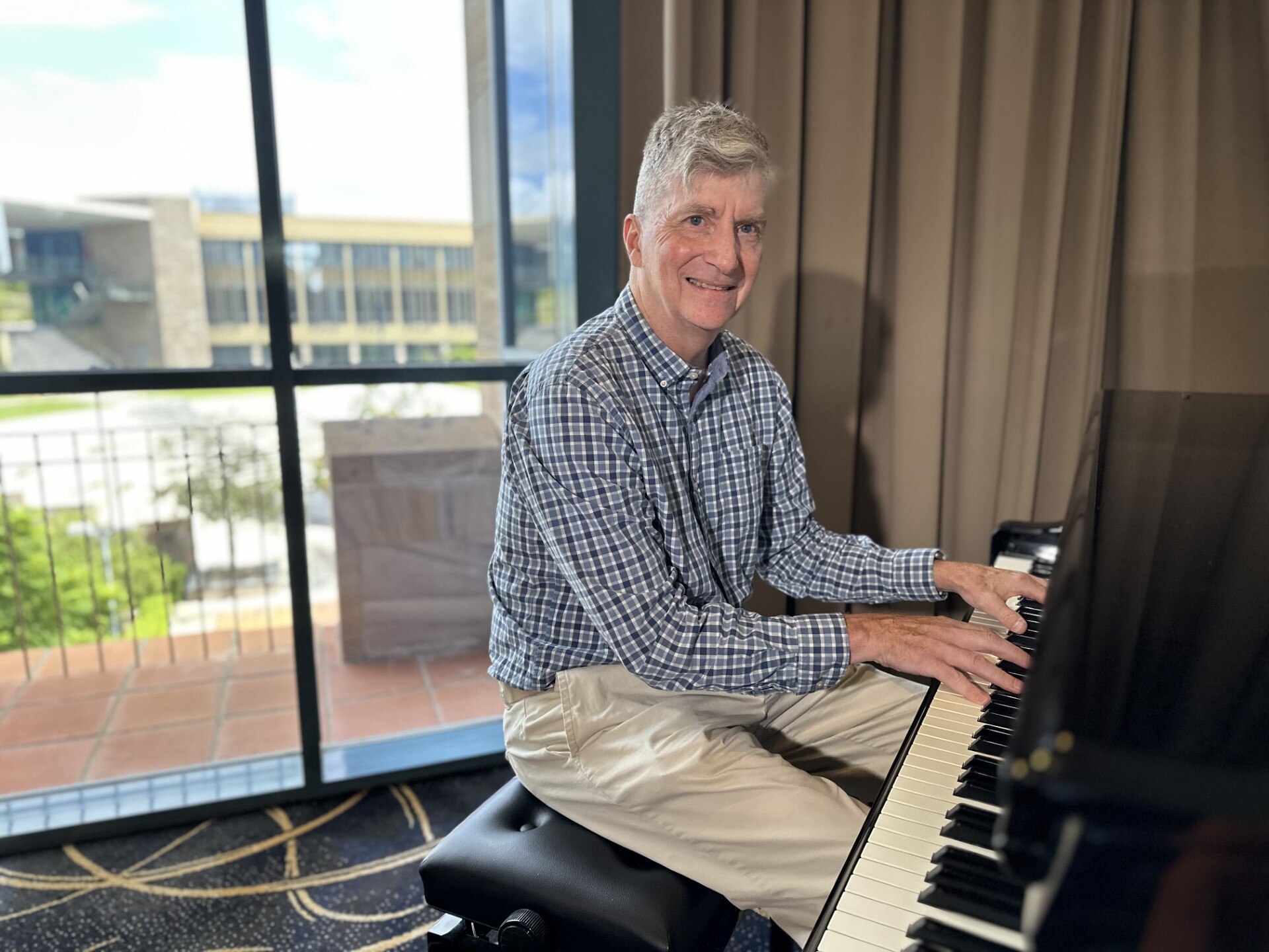 A smiling, middle-aged man plays a pino.