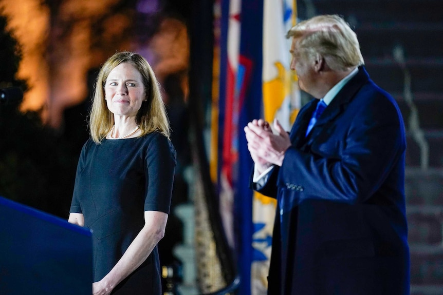 Amy Coney Barrett looking at Donald Trump while he applauds