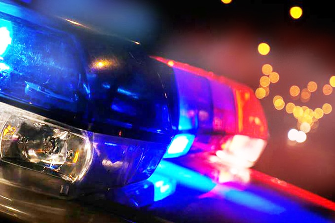 A close-up shows flashing lights at night time on top of a police car.