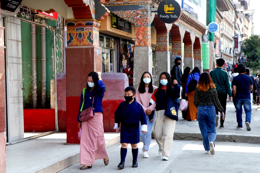 A group of Bhutanese in face masks walking down the street