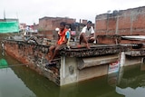 Men sit on the roof of a partially submerged shop.