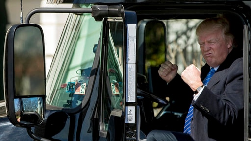 US President Donald Trump gestures with double fists to truckers while sitting inside an 18-wheeler truck at the White House.