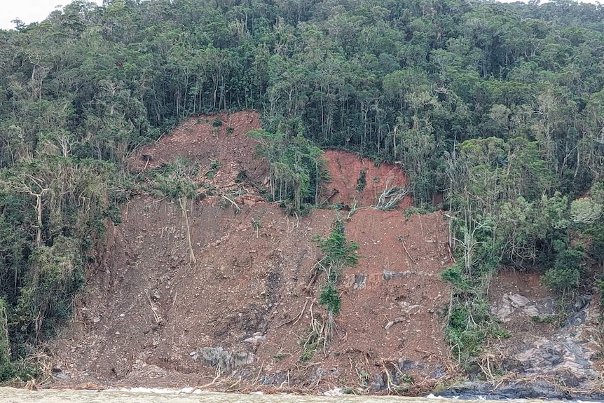 A huge landslide blocking a road through a rainforest.