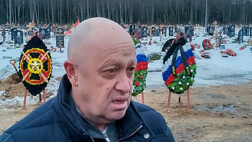 A close up of a bald man wearing a jumper looking off camera in a snowy field.