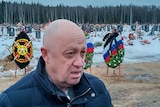A close up of a bald man wearing a jumper looking off camera in a snowy field.