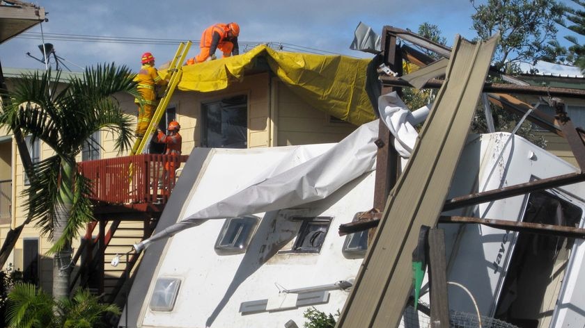 Clean up crews check a house next to a destroyed caravan in Lennox Head