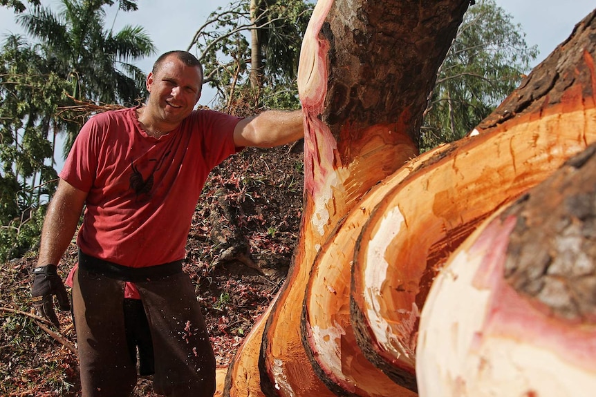 Wood sculptor Joel Mitchell standing next to his artwork as it nears completion.