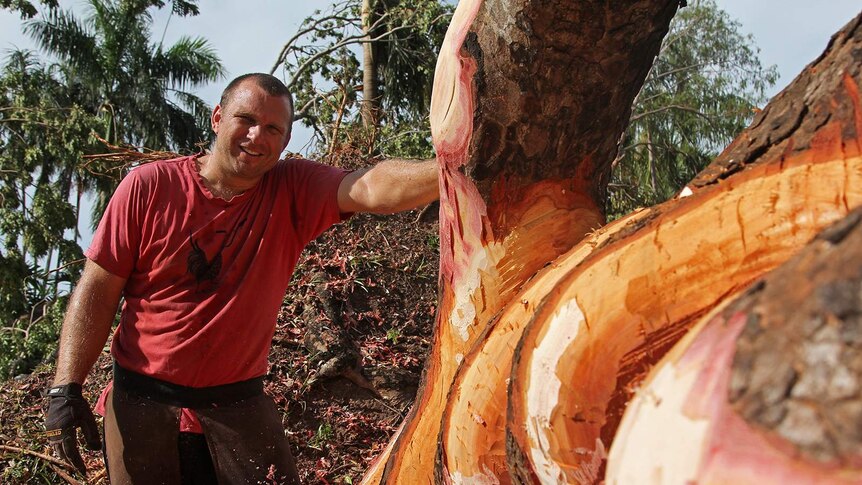 Wood sculptor Joel Mitchell standing next to his artwork as it nears completion.